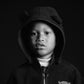 Black and white portrait of a child wearing a bear-themed hoodie against a dark background