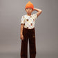 Child wearing an orange beanie, patterned shirt, and brown pants on a gray background