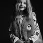Black and white photo of a child wearing a patterned outfit with a hood.