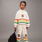 Child wearing a colorful sweater and pants with a bear design, standing against a gray background.
