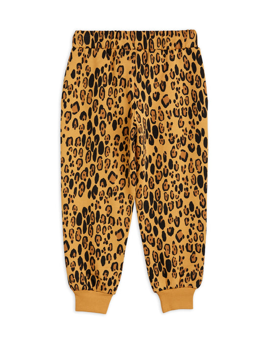 Mini Rodini sweatpants in an abstract leopard print all over pattern. on a beige base there is darker brown and black leopard pattern spots and a drawstring elastic waistband and pinched cuffs at the ankles