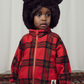 a child in the a Mini Rodini children sbright red with large check pattern fleece jacket, with a gold plated zip and two side pockets and a high neck