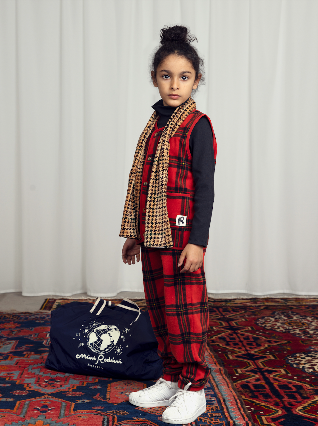 a Child in the Mini Rodini childrens bright red with large check pattern fleece trousers, with an elasticated draw string waistband and two side pockets and elasticated cuffs at the ankles