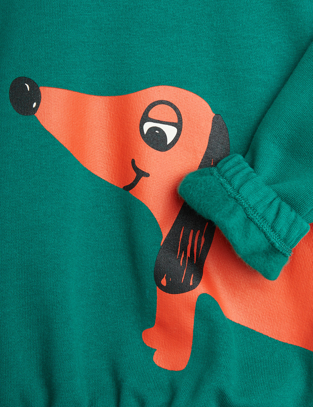 a pair of teal green mini rodini sweatshirt with a printed red sausage dog on the left side of the sweatshirt. with an elasticated waistband and cuffs on the sleeves