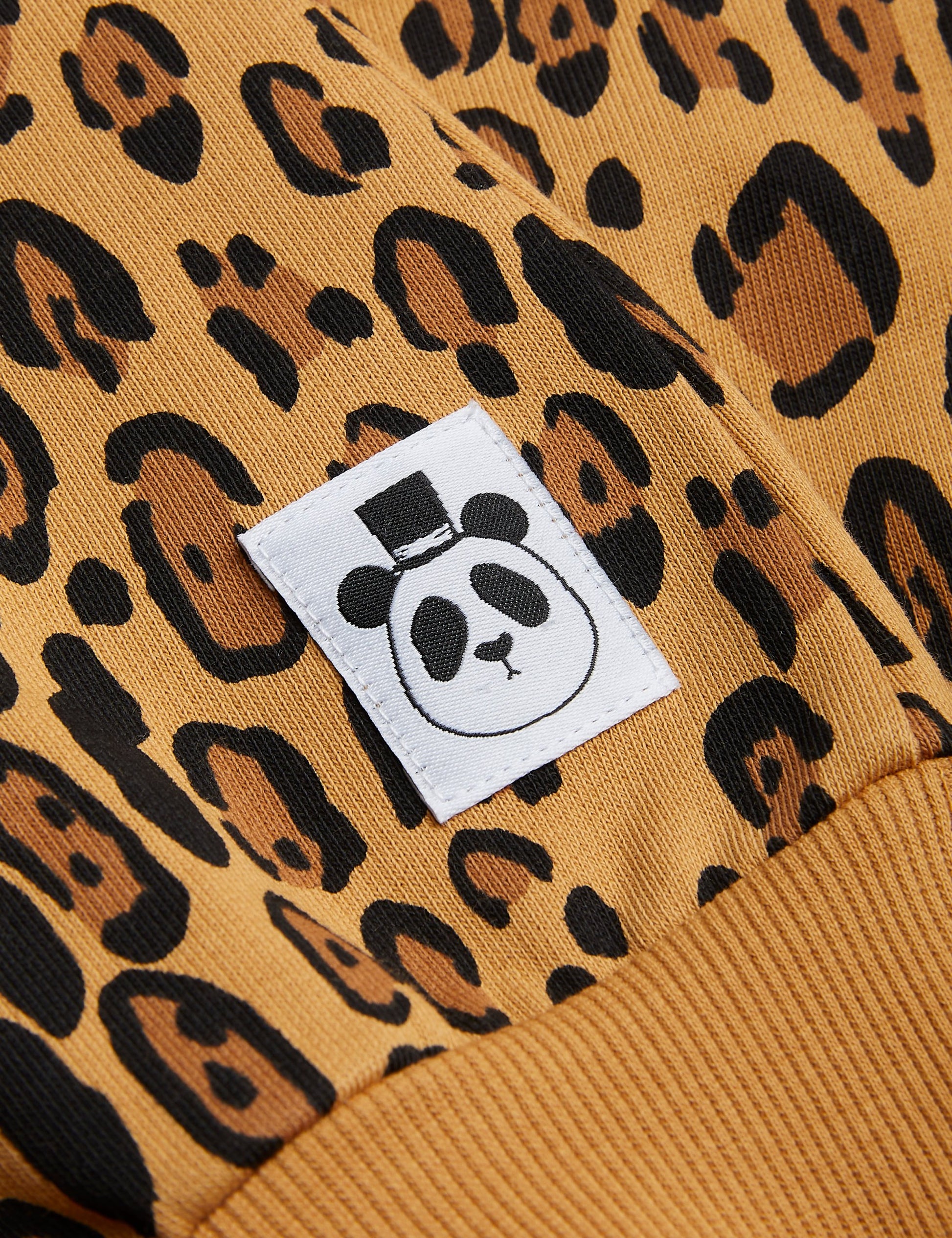  Leopard print Mini Rodini sweatshirt with long sleeves and a baggy fit. the leopard pattern is on a warm beige base with darker brown nd black leopard dots all over