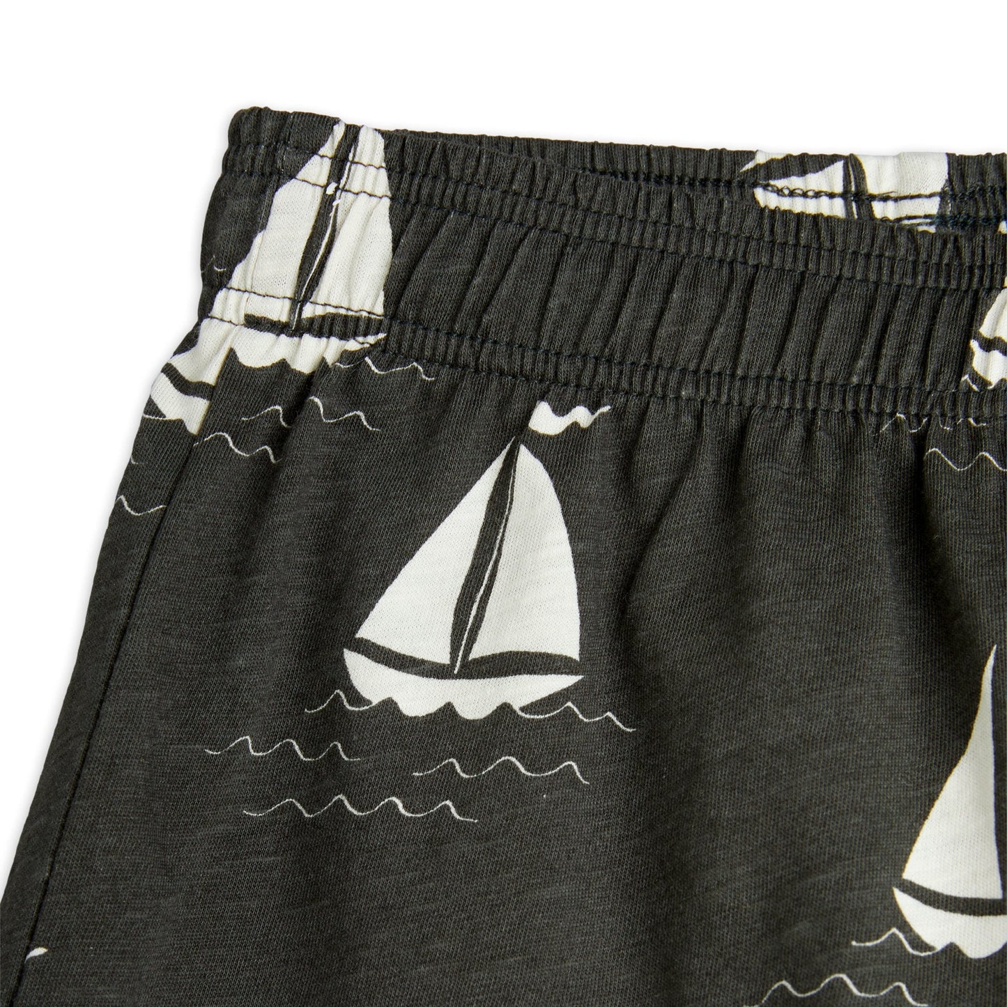 Detailed view of the Mini Rodini sailboat print shorts, highlighting the elasticated waistband and the white sailboat pattern with wavy water details.