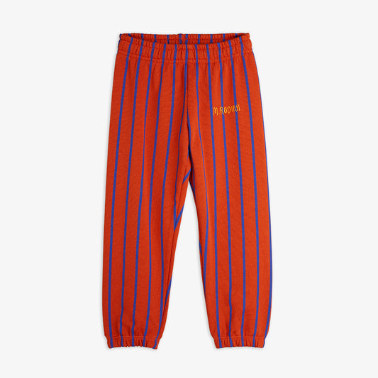 Red Mini Rodini sweatpants featuring bold blue vertical stripes and an embroidered 'M. Rodini' logo on the left leg. Designed with an elasticated waistband and cuffs for a comfortable fit.