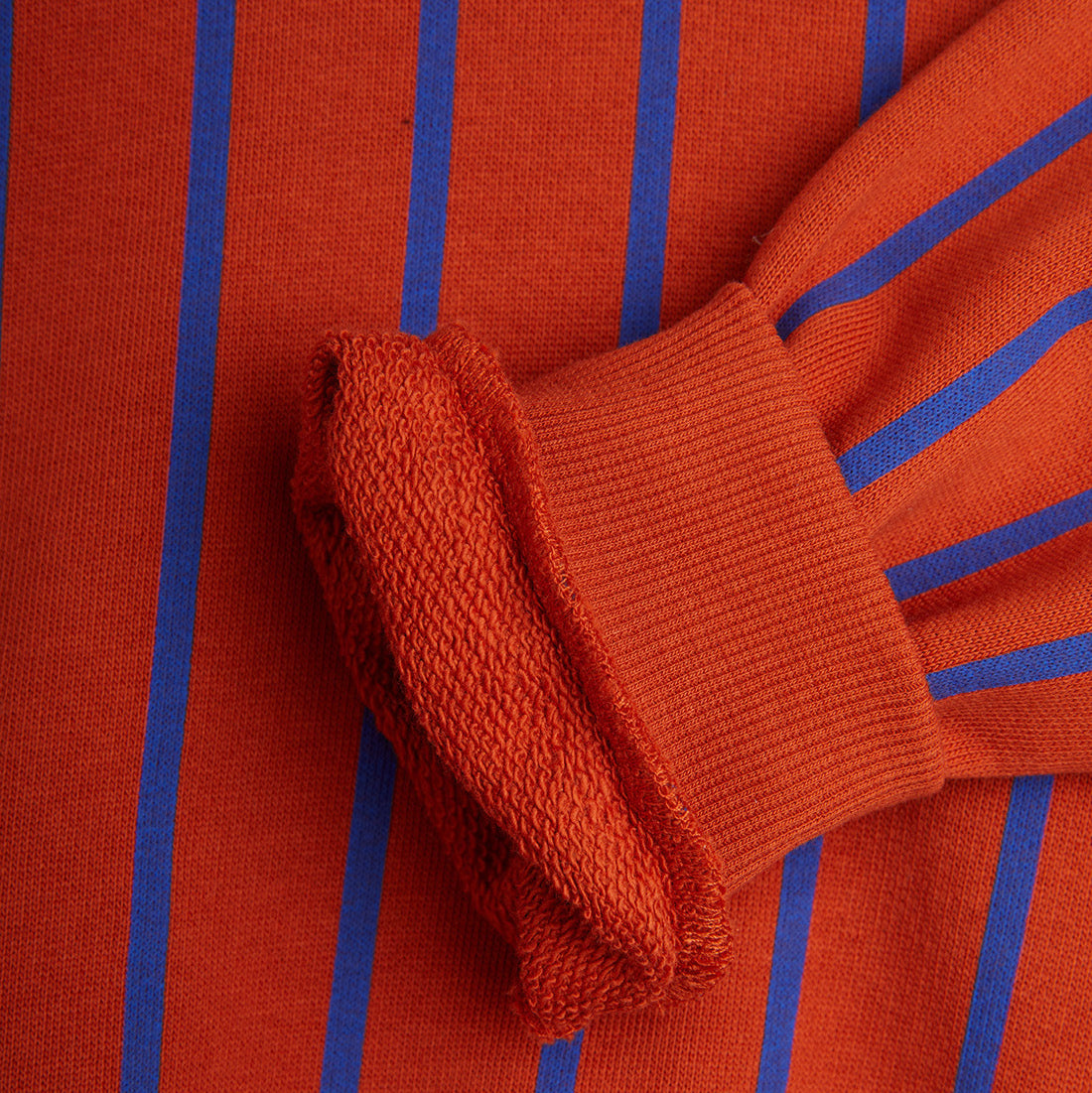 Close-up of the ribbed cuff on the red Mini Rodini stripe sweatshirt, showcasing soft textured fabric and interior lining.