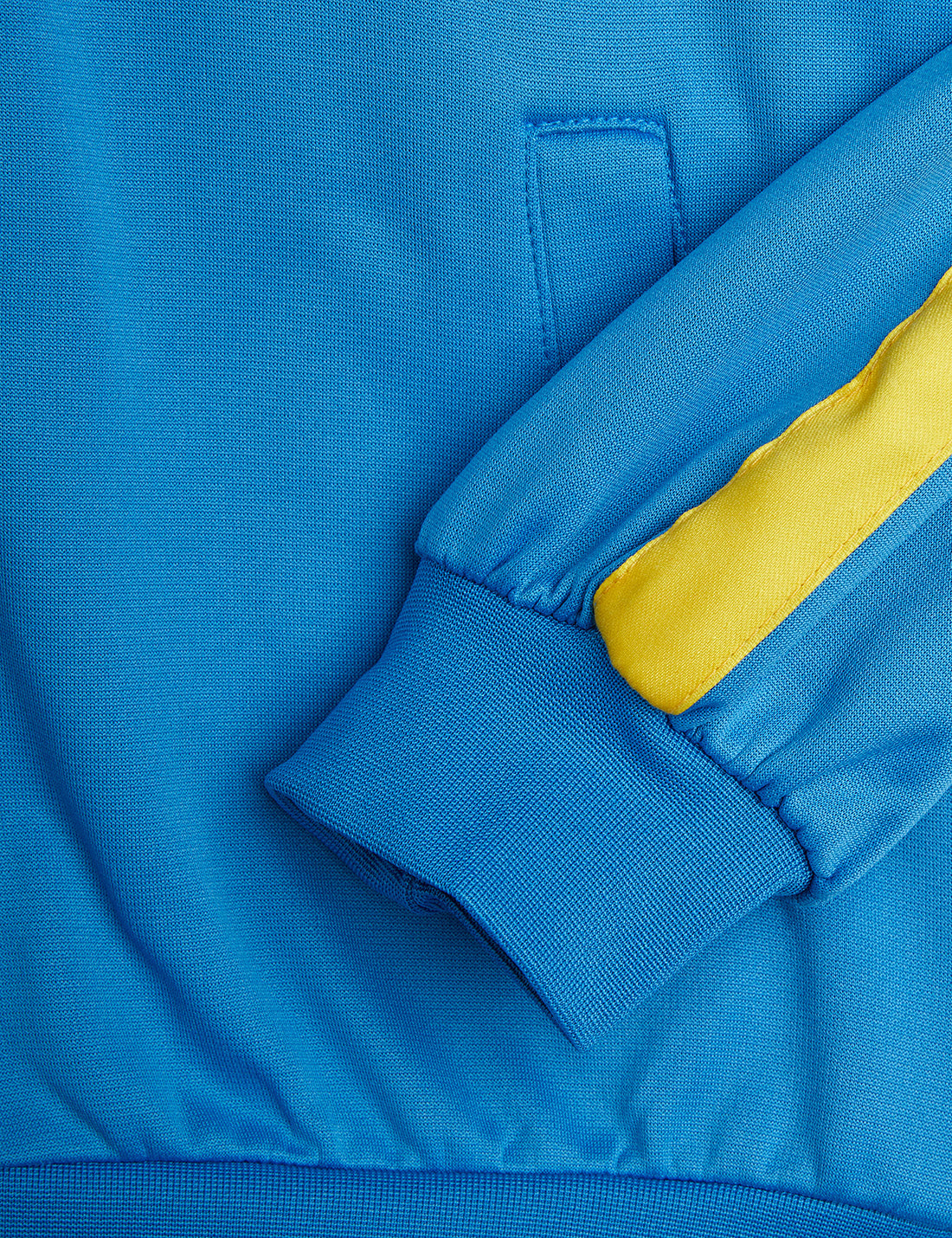 Detailed view of the Mini Rodini WCT hoodie sleeve with a yellow stripe, ribbed cuff, and a front pocket with subtle stitching.