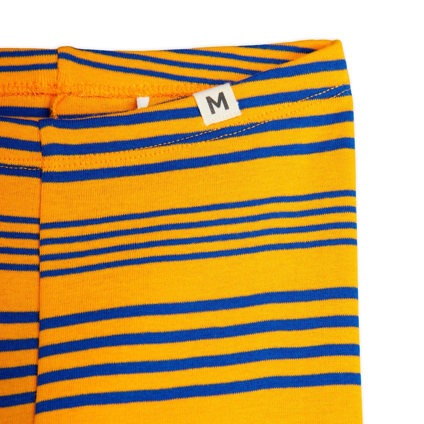 Detailed view of the Mini Rodini ribbed leggings waistband, featuring a small fabric size tag with the letter "M" and neat stitching in yellow with blue stripe accents.