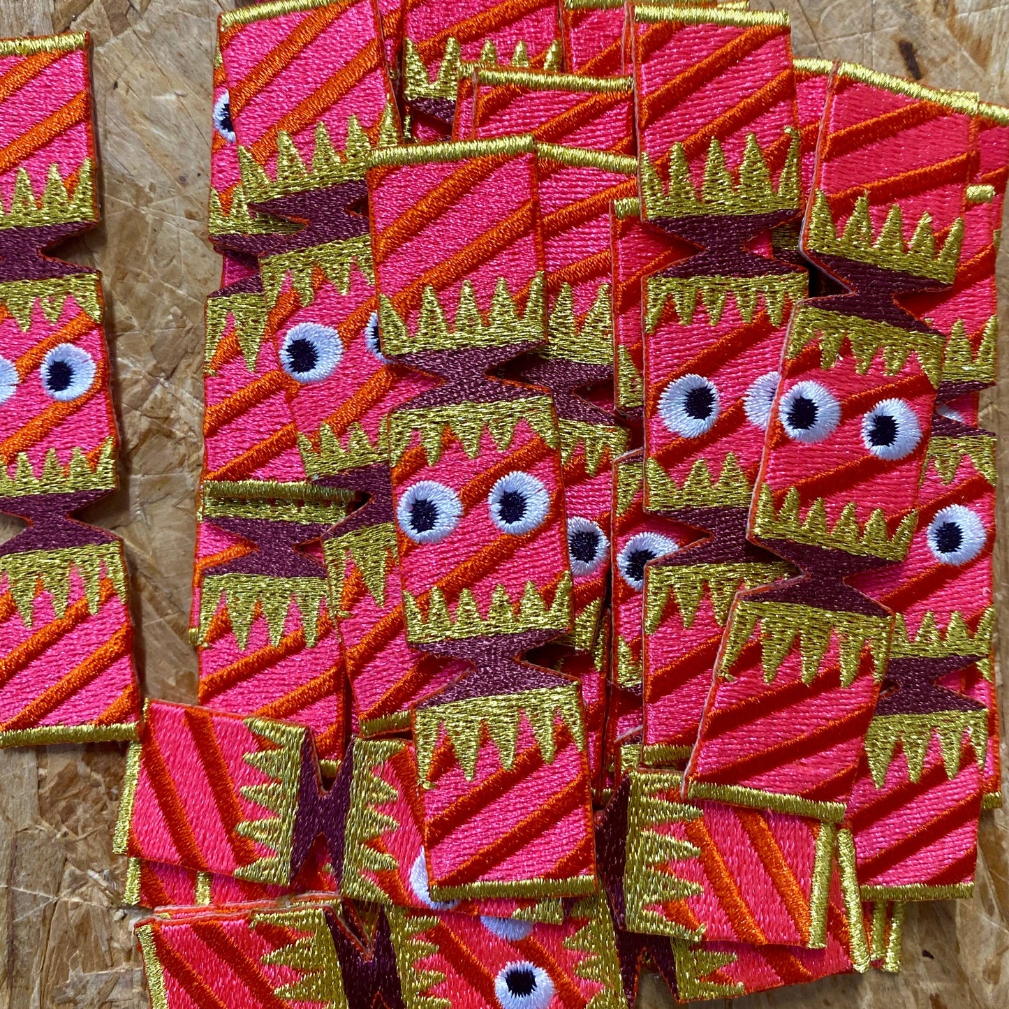 multiple embroidered Christmas crackers with goggly black eyes.It is pink in colour with purple and golden decoration on the wrapper.