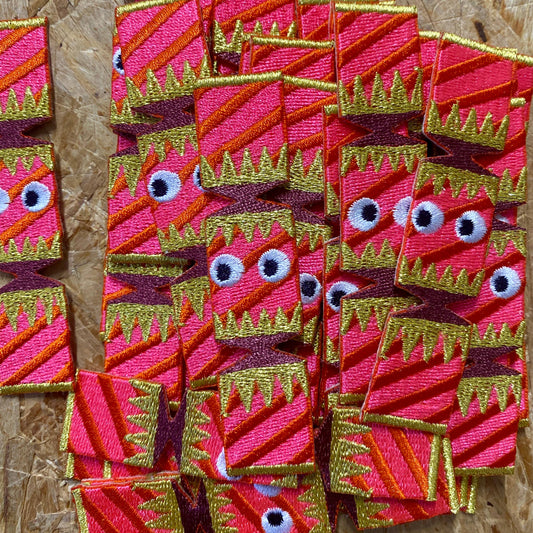 multiple embroidered Christmas crackers with goggly black eyes.It is pink in colour with purple and golden decoration on the wrapper.