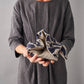 Person holding a folded wheat bag with a pattern against a gray background