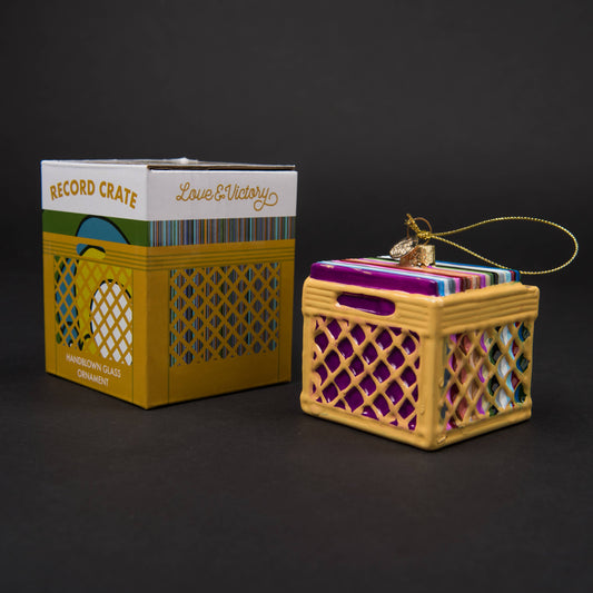 Hand-blown glass record crate ornament featuring hand-painted vinyl records and a yellow milk crate, measuring 3" x 2.5". Packaged in a custom retro holiday box.