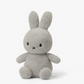 A Miffy Terry soft toy in the colour light grey. This Miffy has black eyes and mouth. Miffy is 23 cm in height. The background is white. 