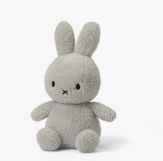 A Miffy Terry soft toy in the colour light grey. This Miffy has black eyes and mouth. Miffy is 23 cm in height. The background is white. 