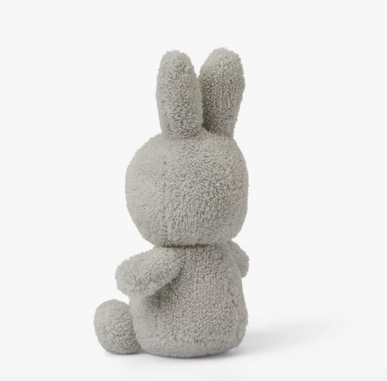 A Miffy Terry soft toy in the colour light grey. This Miffy has black eyes and mouth. Miffy is 23 cm in height. The background is white. This is the back side of Miffy 