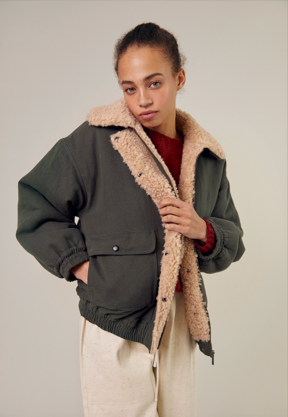 The front view of the Sideline Wilma Jacket, featuring the durable olive cotton twill side facing outward. The jacket showcases a zip front closure, snap-button placket, and rounded collar. The model wears it stylishly, highlighting the sleek design and practical patch pockets, making it an ideal choice for winter wear.