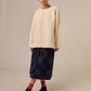 The Sideline Rosa Top, styled on a model who pairs it with a long checked skirt, red ankle socks, and ankle boots. The oversized shearling sweatshirt adds warmth and comfort, while the outfit showcases a trendy mix of textures and patterns, perfect for a stylish winter look.