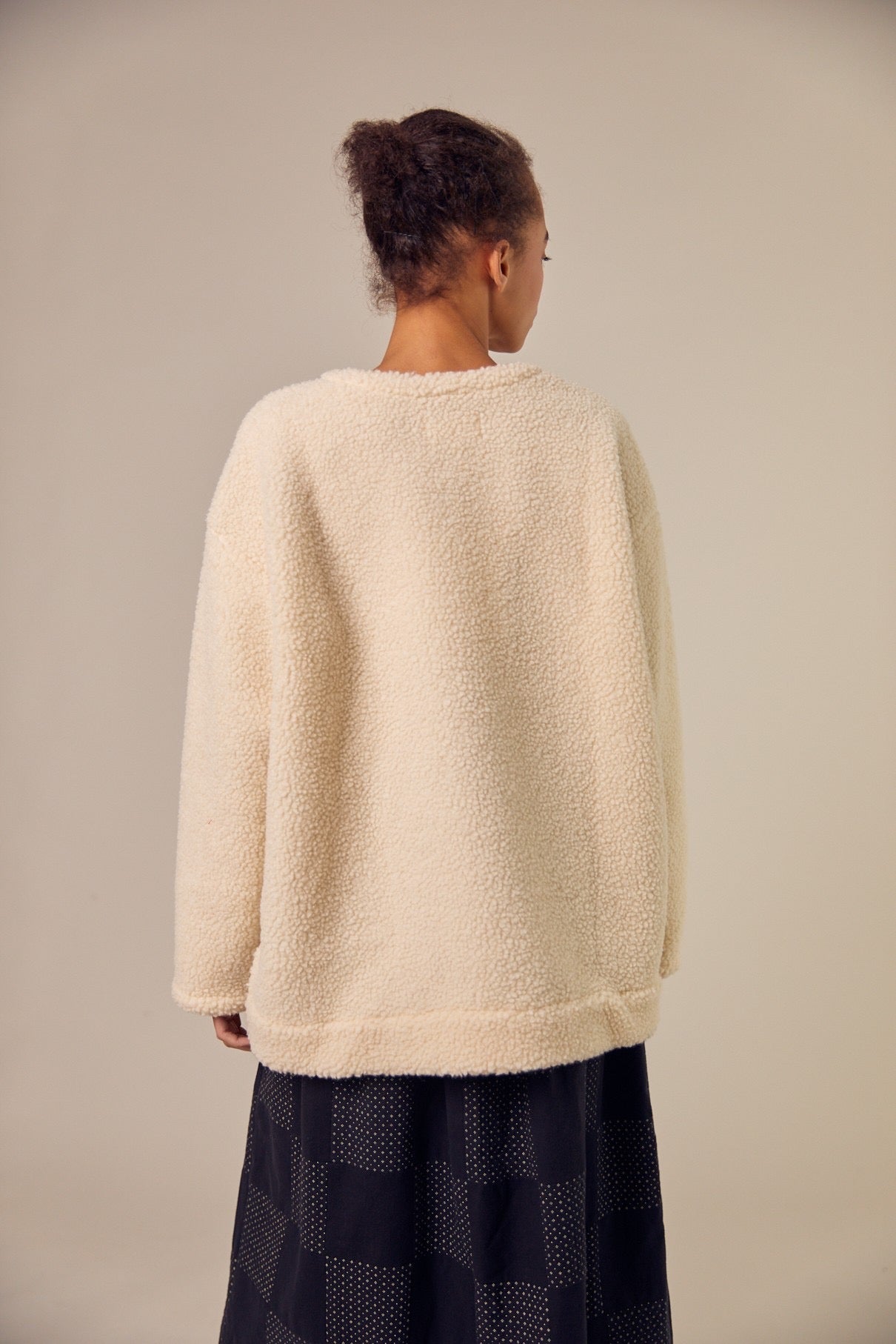 The Sideline Rosa Top shown from the back, highlighting its oversized silhouette and plush shearling texture. The design features a simple, clean line, emphasizing comfort and warmth. This view showcases the top’s versatility, making it an ideal choice for layering or wearing alone during colder months.