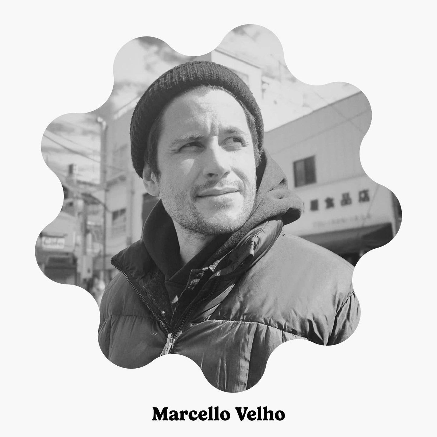 A black-and-white portrait of Marcello Velho, wearing a beanie and a jacket, with an artistic scalloped border framing the image.