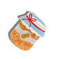 A peanut butter jar-shaped hair claw, featuring a marbled golden-brown body, a white label with a gold-etched peanut icon, and a blue and white gingham-style lid tied with a red bow. The clip is designed with a curved grip and gold detailing, casting a soft shadow against a white background.