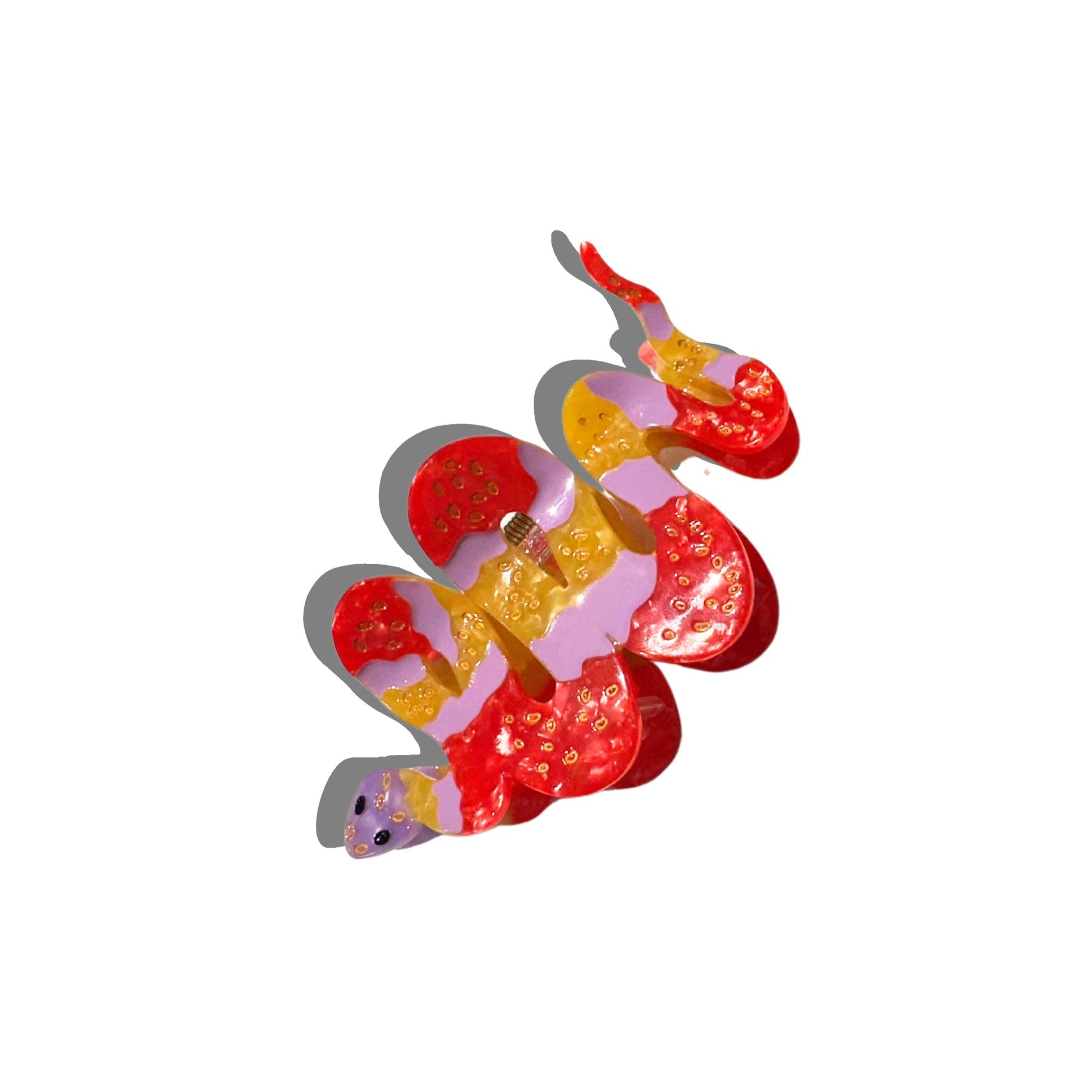 A close-up of the Solar Eclipse hand-painted Snake Claw Clip in a striking mix of red, pink, and yellow with gold detailing. The coiled serpent design is crafted from eco-friendly cellulose acetate and is displayed on a white background, casting a soft shadow.