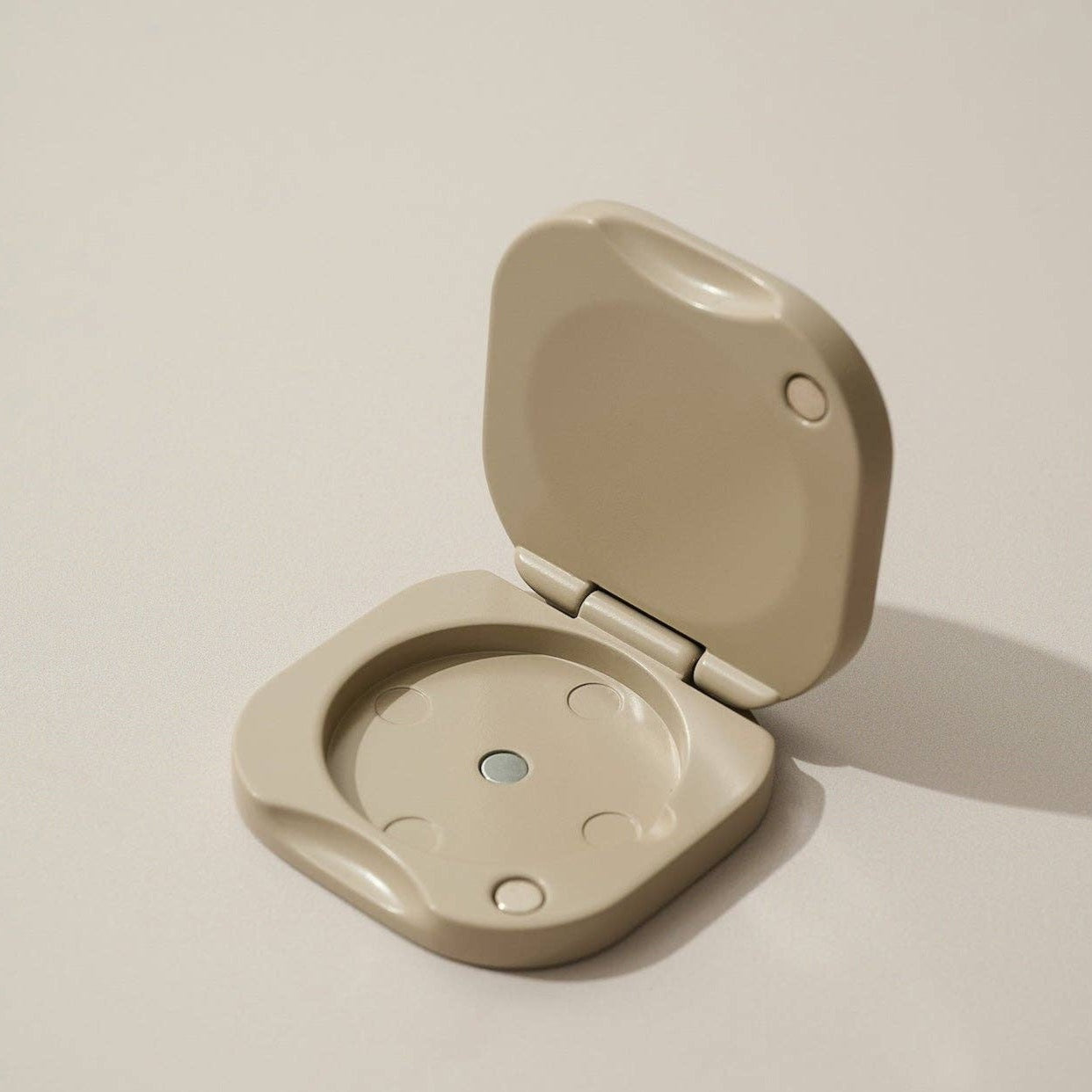 Inside a clay square refillable compact for the tenth muse solid perfume balms that shows the hole in which the soli perfume balm is placed inside of. 