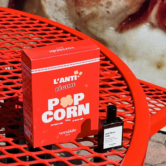 Red 'L'Anti' popcorn box on a red metal chair with a blurred background