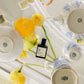 Teacups, a bottle of perfume, and flowers on a white surface
