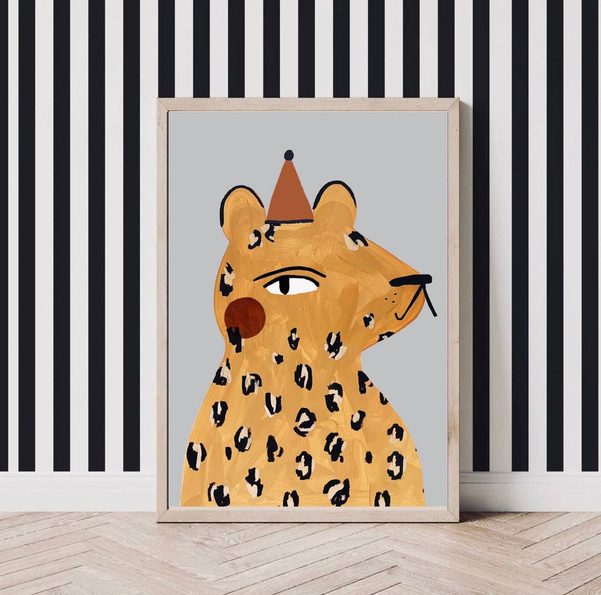 Mr Leopard had red rosy cheeks and wears an orange party hat. The background is a pale blue grey. The frame sits against black and white vertical striped wallpaper