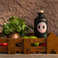 A rustic scene featuring the Yiayia and Friends Extra Virgin Olive Oil bottle in a wooden crate, surrounded by fresh basil, limes, and ripe tomatoes, evoking Mediterranean flavours.