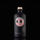 A close-up of the Yiayia and Friends Extra Virgin Olive Oil bottle against a black background, showcasing its minimalist, modern design with a cork top and whimsical illustrated face.