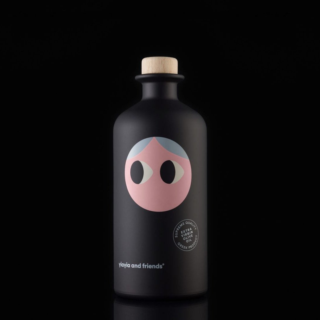 A close-up of the Yiayia and Friends Extra Virgin Olive Oil bottle against a black background, showcasing its minimalist, modern design with a cork top and whimsical illustrated face.