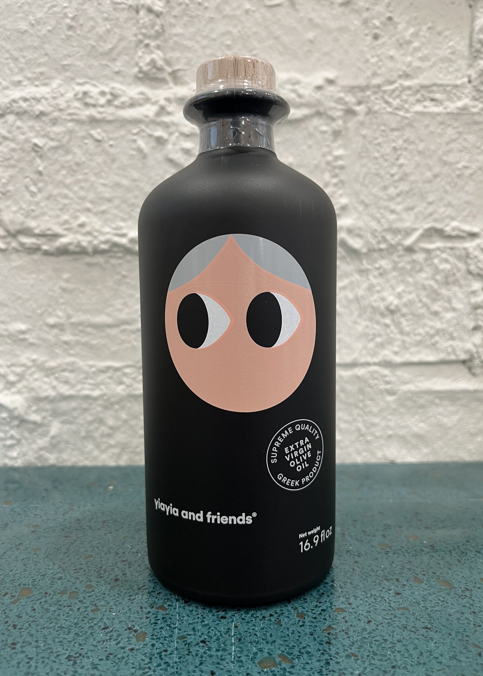 Black bottle with a face design on a textured surface and light gray background