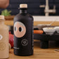 Black bottle with a face design on a wooden surface
