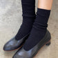 Black socks worn with black shoes on a concrete floor