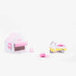 Small toy house with pink roof and canopy, and a toy car on a white background