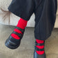 Black shoes with red sock on a concrete floor.