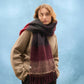 Person wearing a large, multicolored scarf against a blue background