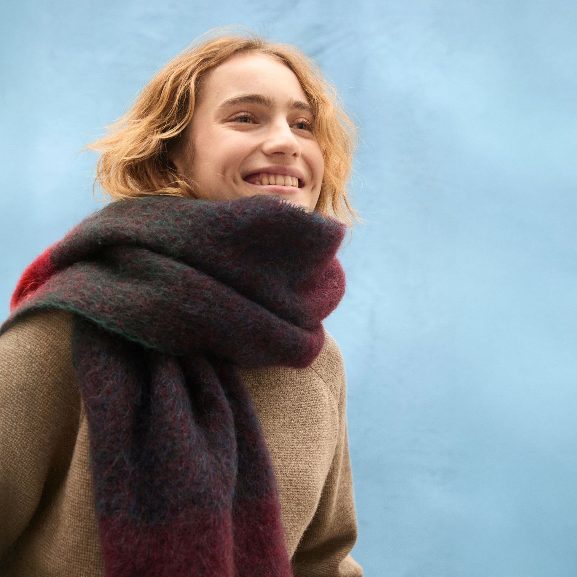 Person wearing a colorful scarf against a blue background