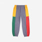 Color-blocked pants with gray, yellow, red, and green sections on a white background