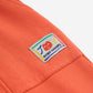 A close-up of the sweatpants’ side pocket, which has a colourful, playful "JOY" logo patch from Bobo Choses.