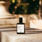 Perfume bottle labeled 'Exscentric Molecules' on a stone surface with blurred background