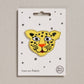 Yellow leopard patch on a white card with star patterns, displayed on a beige background.