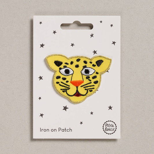Yellow leopard patch on a white card with star patterns, displayed on a beige background.