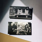 Two black and white photographs displayed on a wall with a spotlight effect.