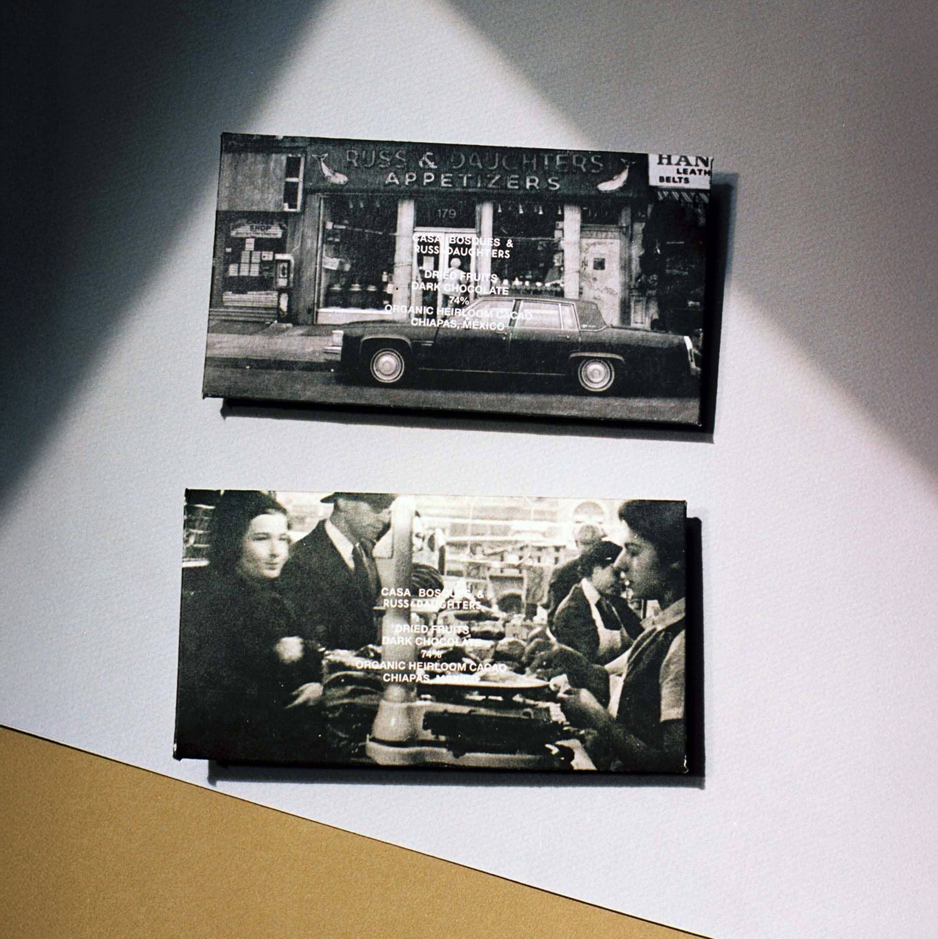 Two black and white photographs displayed on a wall with a spotlight effect.