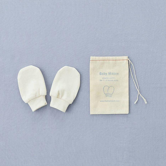 two little baby cream cotton mittens next to one another, with rounded edges and a tighter elastic section by the wrists. with a draw string bag with an illustration f the two mittens and the fg linen logo