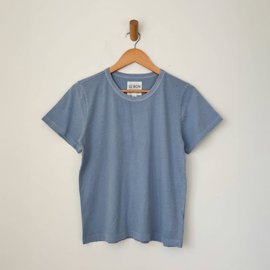 a light blue cotton shirt with a masculine boxy shape, without the long length. short sleeve and distressed details on the sleeve and bottom edges